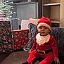 Shayana participe au concours pour gagner de l'argent avec cette photo : baby, child, santa_hat, santa_costume, christmas_presents, wrapped_gifts, christmas_tree, fairy_lights, decorations, pillow, cushion, wooden_floor, indoor, lamp, shelf, holiday, festive, sitting, portrait, cute