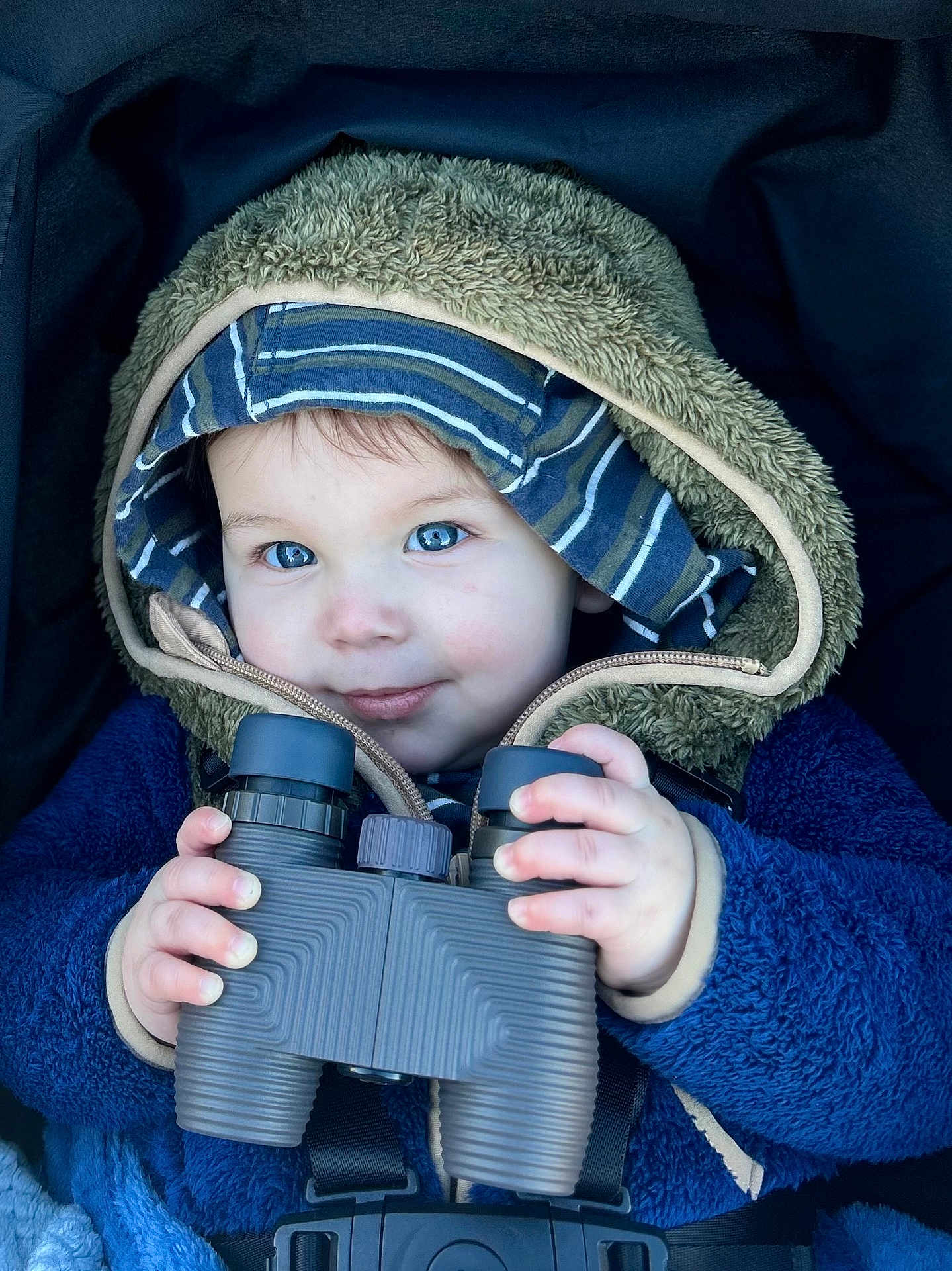 Carson is registered to the contest to win money with this photo: toddler, child, binoculars, hooded_jacket, blue_eyes, striped_hat, winter_clothing, cozy, curious, hands, portrait, baby, cute, outdoor_gear, warm, face, smile, young_child, close_up, exploration