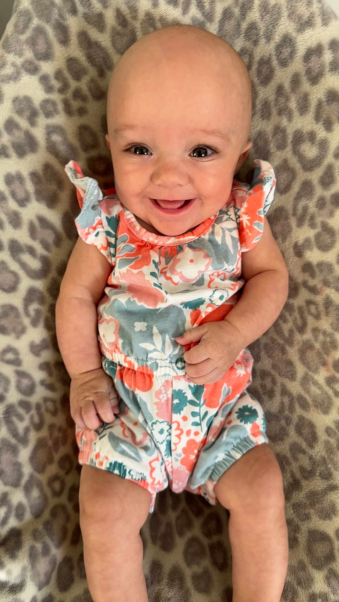 Ayla is registered to the contest to win money with this photo: baby, smiling, infant, floral_clothing, romper, leopard_print, blanket, lying_down, happy, cute, child, person, skin, head, eyes, arms, legs, comfort, indoors, portrait