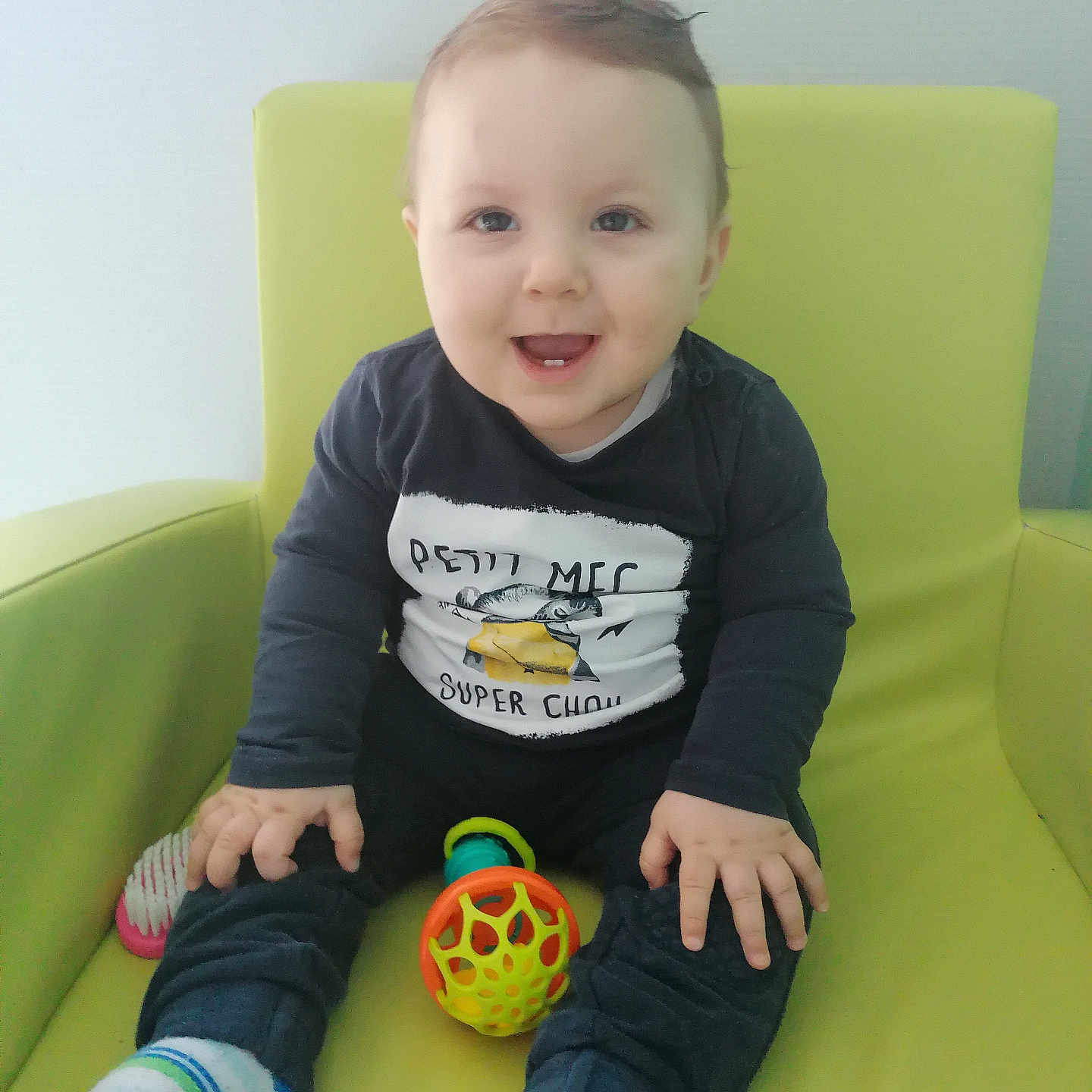 Kaydon participe au concours pour gagner de l'argent avec cette photo : baby, bright, chair, child, clothing, comfort, cute, face, feet, hand, happy, indoor, infant, person, playful, portrait, sitting, smiling, sock, toy