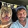 man, dog, selfie, car, smile, happy, cap, tattoo, pet, inside, seat, window, leash, tongue_out, beard, casual, friendship, closeup, portrait, daylight