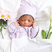 Thalia is registered to the contest to win money with this photo: newborn, baby, sleeping, portrait, lavender, hat, onesie, blanket, flowers, daisy, lily, white_background, bed, indoor, peaceful, infant, face, closed_eyes, floral_arrangement, photography