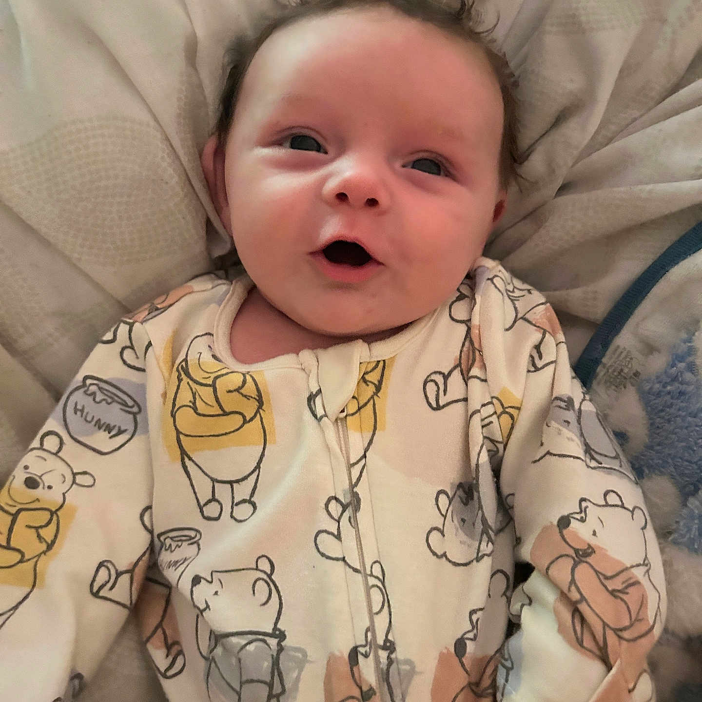 Finley is registered to the contest to win money with this photo: baby, blanket, child, clothing, comfort, cozy, cute, expression, face, happy, indoors, infant, lying_down, onesie, pattern, sleepwear, smiling, soft, winnie_the_pooh, young_child