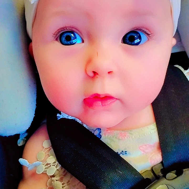 Baylee joined the competition — help win amazing prizes! baby, blue_eyes, bow, bracelet, car_seat, child, child_safety, closeup, clothing, cute, expression, face, hand, headband, infant, portrait, seatbelt, sitting, skin, young