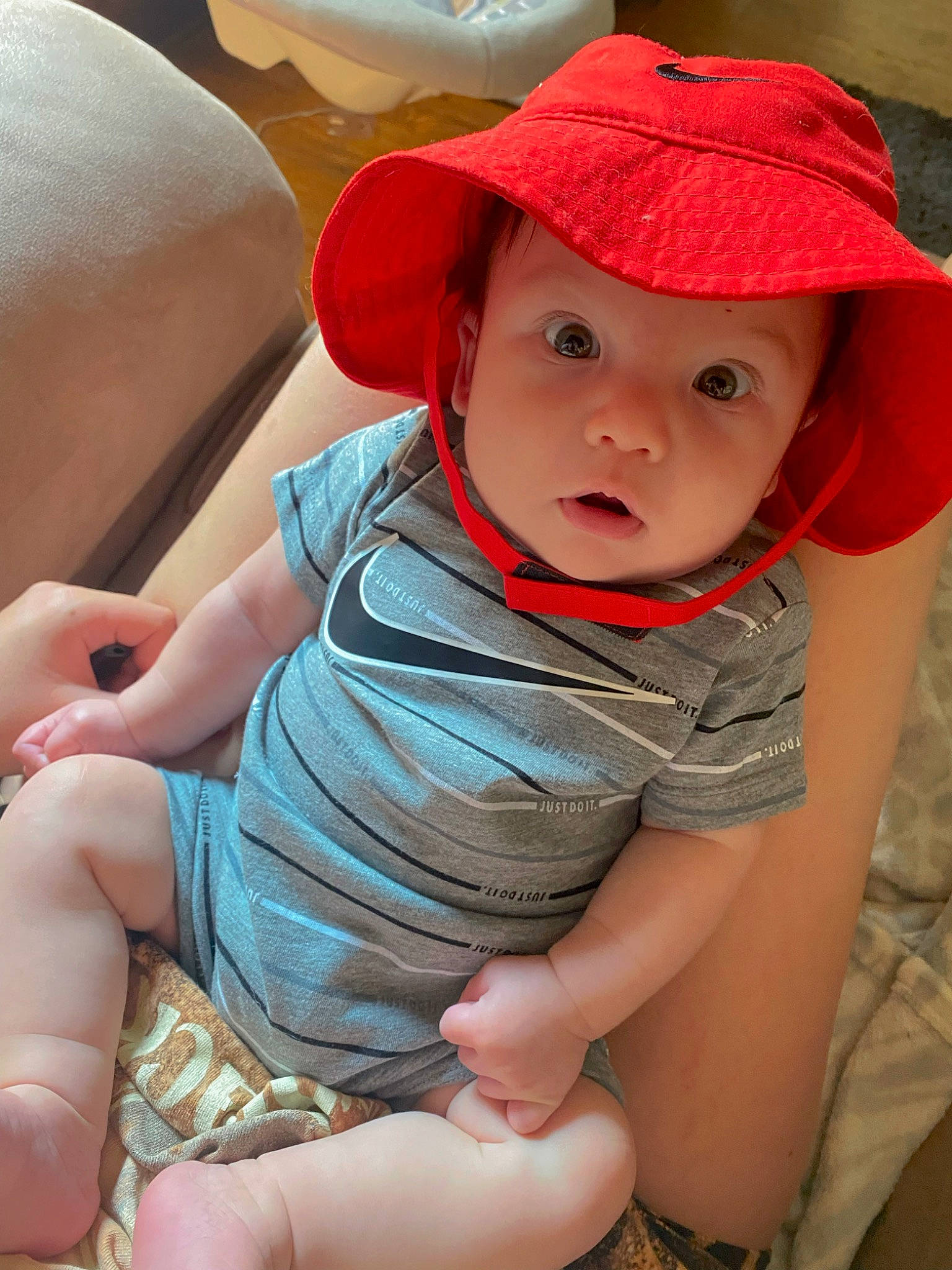 Holden is registered to the contest to win money with this photo: baby, baby_toddler_clothing, baseball_cap, cap, cheek, comfort, elbow, eye, finger, hand, happy, hat, headwear, human_leg, lip, person, skin, sleeve, sun_hat, surprise