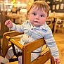 baby, child, high_chair, wooden_furniture, indoor, restaurant, curious, blue_clothing, striped, seated, infant, face, eyes, soft_lighting, bokeh, table, wooden_floor, casual, cute, portrait