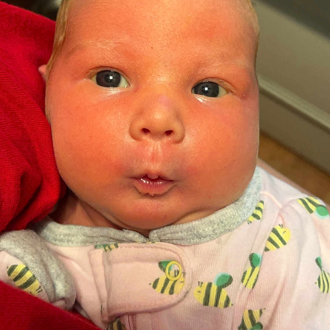 Cora is registered to the contest to win money with this photo: baby, blanket, bodypart, clothing, crib, cushion, face, furniture, head, homedecor, infantbed, knitwear, mouth, newborn, person, photography, portrait, quilt, selfie, sweater