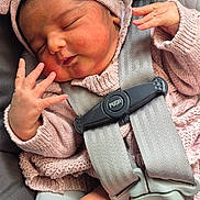 Mia is registered to the contest to win money with this photo: baby, sleeping, car_seat, pink_clothing, headband, knitwear, infant, child, safety_harness, cute, peaceful, hand, face, newborn, soft_texture, seat_belt, portrait, indoors, resting, cozy