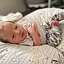 Levi is registered to the contest to win money with this photo: baby, infant, pillow, pattern, animal_print, clothing, camouflage, face, eyes, hand, lying_down, bedroom, soft_lighting, cute, newborn, child, portrait, resting, indoors, comfort