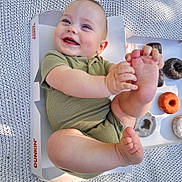 Damian joined the competition — help win amazing prizes! baby, child, smiling, dunkin, donuts, box, foot, hand, green_clothing, blanket, cute, happy, infant, sitting, playful, skin, outdoor, food, snack, portrait