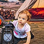 toddler, child, lantern, camping, tent, firewood, outdoor, curly_hair, blue_eyes, crawling, adventure, nature, explorer, casual_clothing, soft_lighting, ground, playful, daylight, portrait, cute
