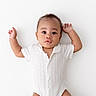 Desmond is registered to the contest to win money with this photo: baby, infant, child, white_background, onesie, curious, lying_down, raised_arms, portrait, cute, adorable, expression, face, skin, hair, small_hands, newborn, peaceful, studio_shot, minimalist