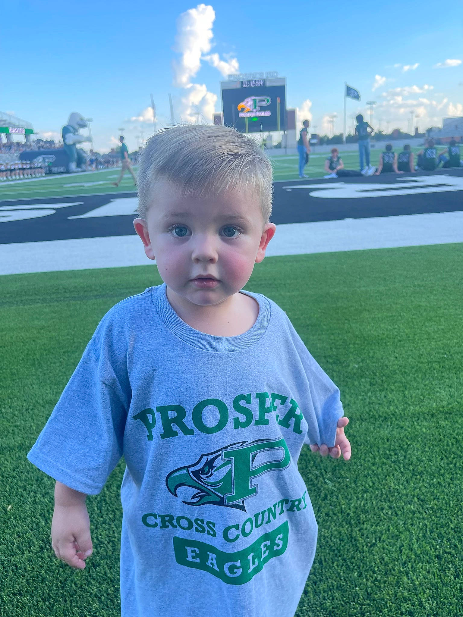 Holden is registered to the contest to win money with this photo: baby_toddler_clothing, child, cloud, cool, fun, grass, grass_family, grassland, happy, lawn, leisure, meadow, person, photograph, plant, sky, sleeve, standing, summer, t_shirt