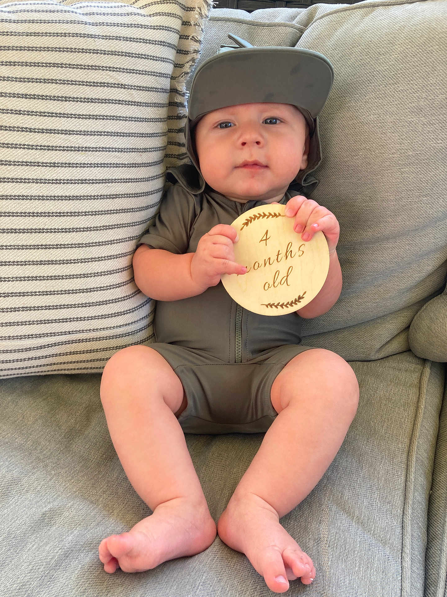 Stetson Hayes is registered to the contest to win money with this photo: baby, infant, child, couch, pillow, wooden_sign, hat, clothing, sitting, legs, feet, hands, face, expression, home, indoor, fabric, striped_pillow, cute, comfortable