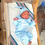 Jalen is registered to the contest to win money with this photo: baby, blanket, blue_onesie, cozy, face, foot, hand, hat, hospital, hospital_bassinet, indoors, infant, newborn, nursery, peaceful, person, sleep, sleeping, striped_blanket, wooden_bassinet