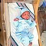 baby, blanket, blue_onesie, cozy, face, foot, hand, hat, hospital, hospital_bassinet, indoors, infant, newborn, nursery, peaceful, person, sleep, sleeping, striped_blanket, wooden_bassinet