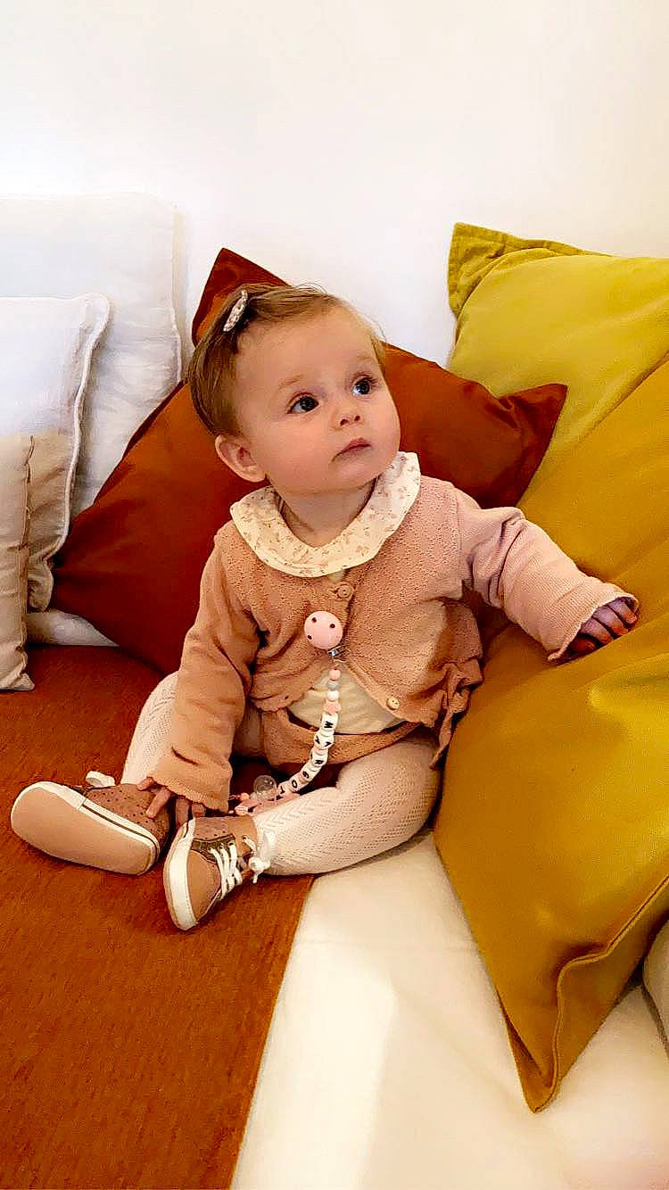 Margot participe au concours pour gagner de l'argent avec cette photo : baby, baby_toddler_clothing, child, comfort, couch, fashion_accessory, flooring, fun, happy, human_leg, jewellery, knee, leg, person, sitting, skin, sleeve, sock, thigh, toddler