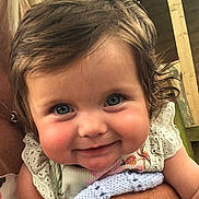 Sienna joined the competition — help win amazing prizes! baby, child, blue_eyes, smile, face, cute, person, infant, holding, hand, knitted_blanket, white_dress, lace, rosy_cheeks, portrait, closeup, warmth, indoor, wood_background, happy