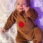 Louie joined the competition — help win amazing prizes! baby, infant, onesie, reindeer, costume, smile, face, person, child, blanket, soft_texture, cute, holiday, christmas, fur, lying_down, cozy, warm_clothing, indoors, happy
