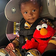 Omari joined the competition — help win amazing prizes! child, toddler, car_seat, seat_belt, plush_toy, elmo, pajamas, car_interior, sunlight, cute, smiling, face, hand, clothing, toy, seat, window, safety, happy, infant