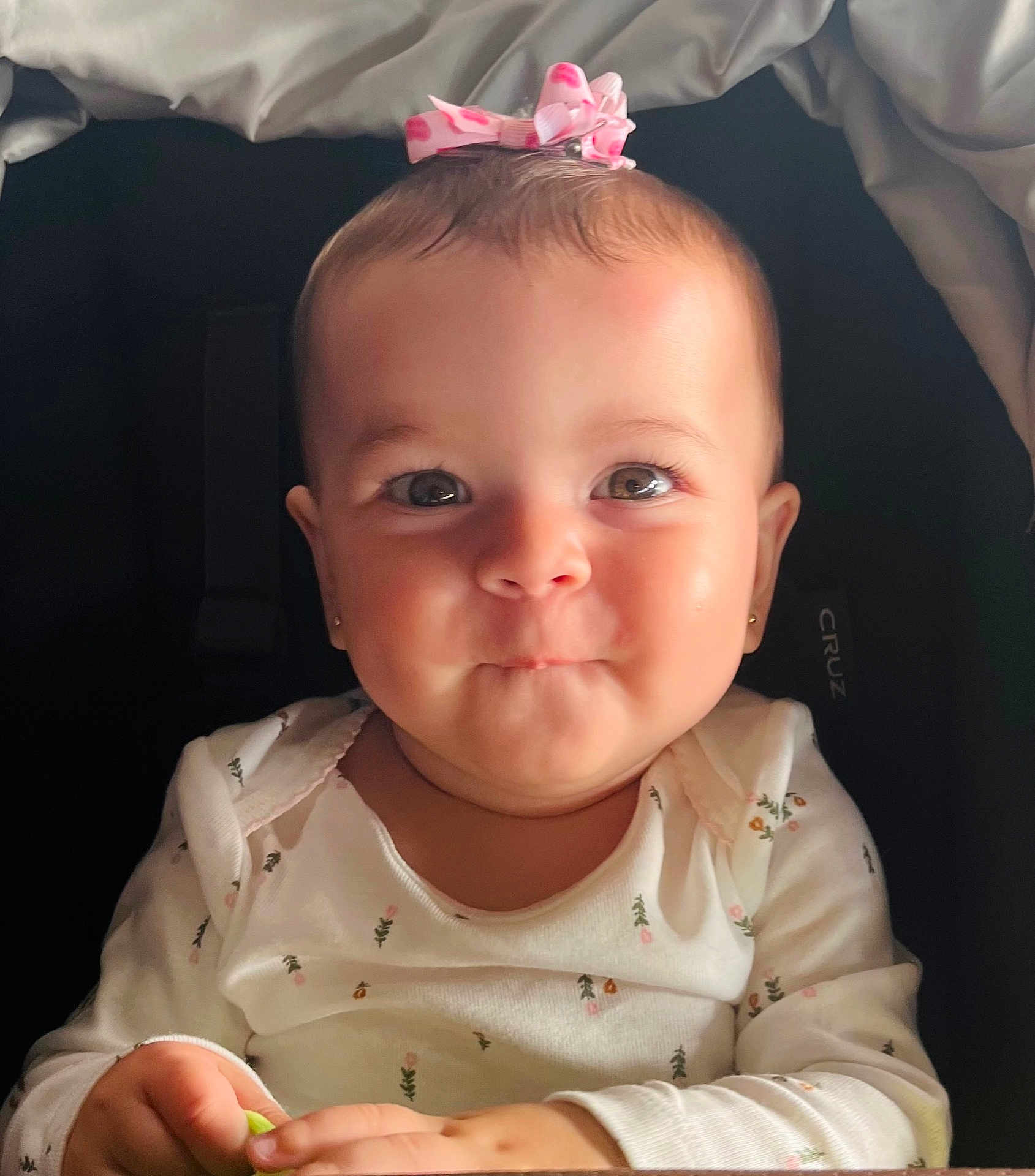 Sophia joined the competition — help win amazing prizes! baby, infant, child, smile, face, eyes, bow, hair, clothing, white, floral, cute, portrait, indoors, hands, sitting, adorable, expression, person, young