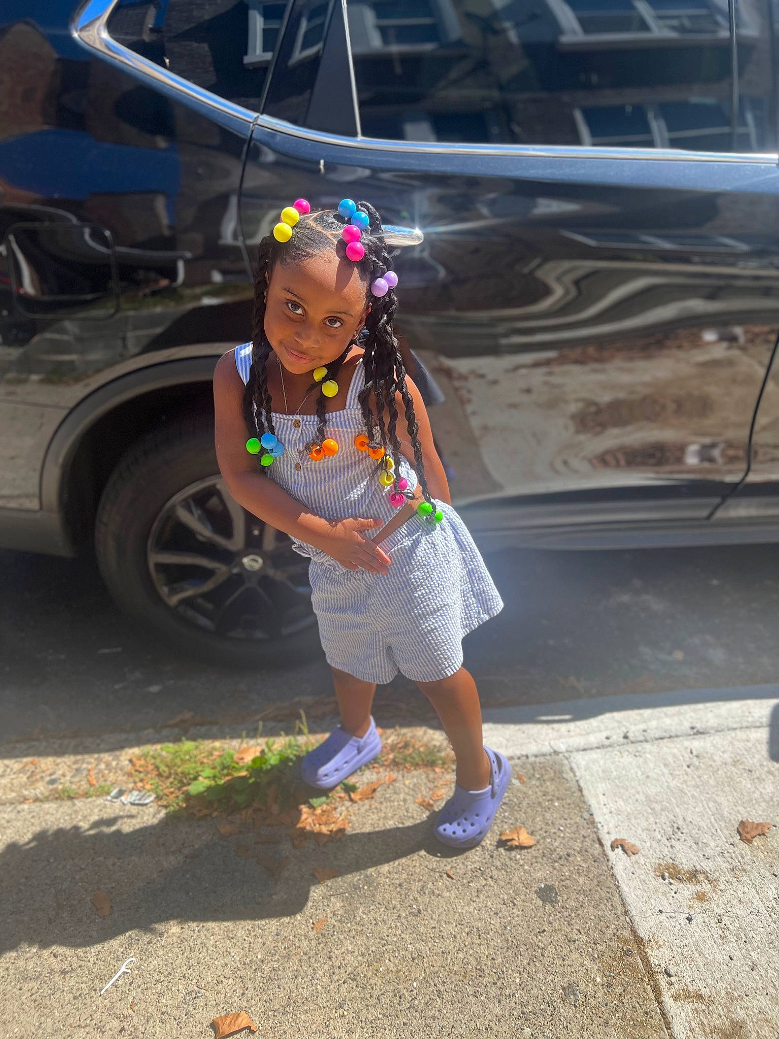 Amani is registered to the contest to win money with this photo: asphalt, automotive_tire, child, electric_blue, event, fun, hat, headwear, human_leg, leg, leisure, person, recreation, road, road_surface, sandal, shorts, sidewalk, tire, toddler