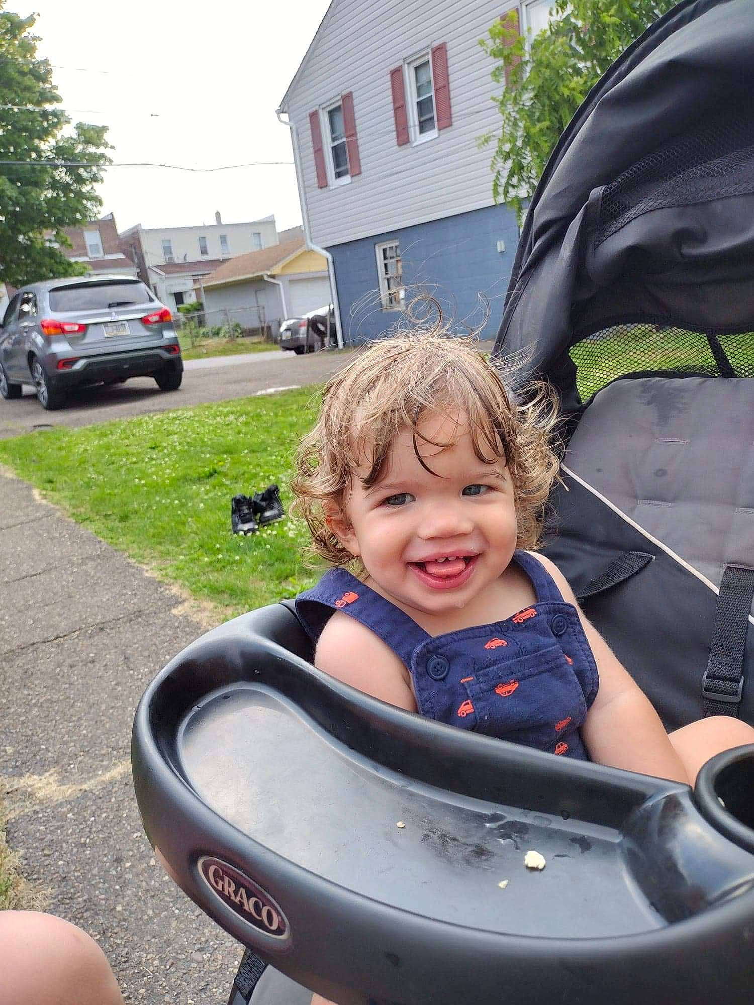 Dawson is registered to the contest to win money with this photo: auto_part, automotive_exterior, automotive_tire, automotive_wheel_system, baby_carriage, baby_products, car, child, grass, joy, motor_vehicle, person, plant, sitting, sky, smile, tire, toddler, tree, vehicle