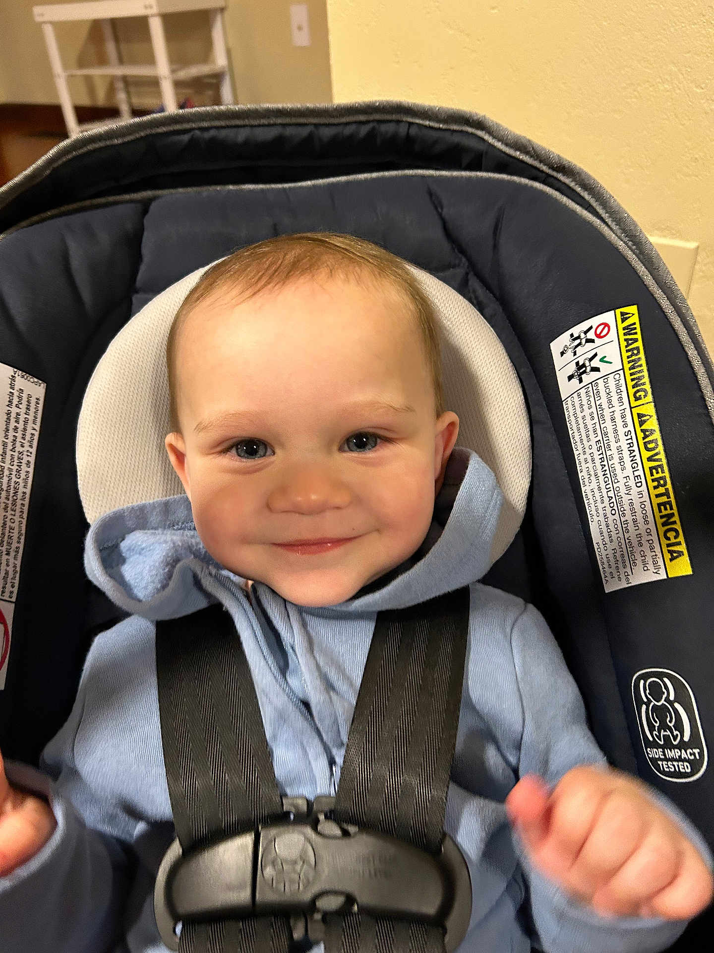 Rory is registered to the contest to win money with this photo: baby, child, car_seat, blue_hoodie, smile, happy, face, infant, straps, indoor, seatbelt, safety, headrest, clothing, person, cute, portrait, small_child, baby_boy, closeup