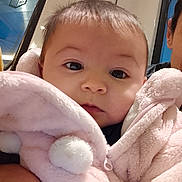 Leya a rejoint le concours — aidez-le/la à gagner de superbes lots ! baby, infant, child, portrait, close_up, pink_jacket, fluffy, pompom, face, eyes, cheeks, cozy, candid, parent_partial, public_transport, window, signage, soft_toy, hooded_jacket, indoor