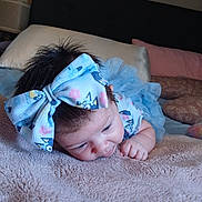 Katie is registered to the contest to win money with this photo: baby, bedroom, blanket, blue_dress, bow, child, closeup, curly_hair, cute, face, hand, headband, indoors, infant, lying_down, person, pillow, sleepwear, soft_texture, toddler