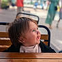 blurry_background, casual, child, clothing, cute, daylight, expression, face, hair, happy, outdoor, people, person, portrait, public_space, seat, smiling, table, toddler, wooden_table