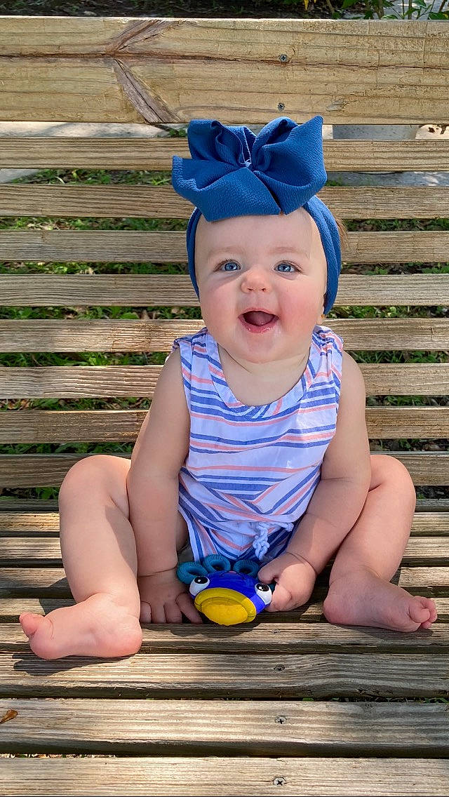 Karsyn is registered to the contest to win money with this photo: baby, baby_toddler_clothing, blue, chin, clothing, eye, face, facial_expression, grass, happy, head, headwear, human, person, pink, purple, skin, sleeve, smile, standing
