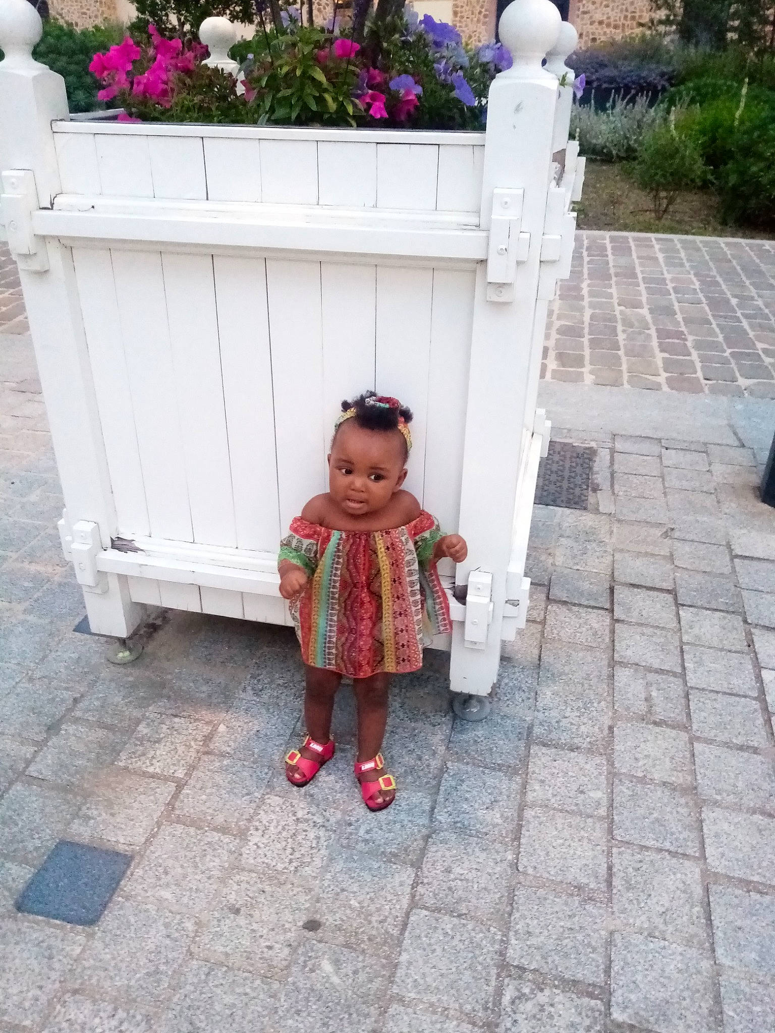 Elena participe au concours pour gagner de l'argent avec cette photo : baby_products, baby_toddler_clothing, child, flooring, flower, grass, leaf, leisure, outdoor_furniture, pattern, person, pink, plant, public_space, road_surface, shrub, sidewalk, sunglasses, toddler, tree