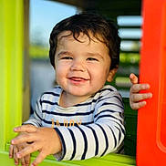 Adam a rejoint le concours — aidez-le/la à gagner de superbes lots ! toddler, child, smiling, playhouse, window, striped_shirt, hands, happy, outdoor, daylight, face, cute, young_child, play, joyful, person, portrait, colorful, fun, baby