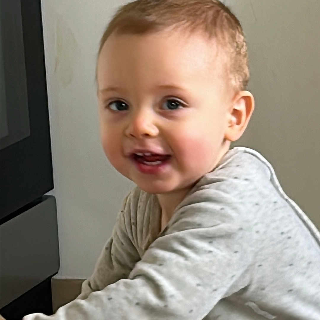 Ezio participe au concours pour gagner de l'argent avec cette photo : baby, child, clothing, curious, exploring, expression, face, floor, head, indoor, kitchen, leaning, light, long_sleeve, person, playful, smiling, tile, toddler, young_child