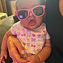 Ivanka is registered to the contest to win money with this photo: baby, casual, child, colorful, cozy, cute, fruit, funny, hand, holding, indoor, infant, lap, onesie, pattern, person, pink_sunglasses, portrait, reflection, smiling_faces