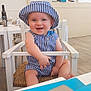 baby, child, smiling, hat, striped_clothing, high_chair, indoor, cafe, wooden_chair, happy, person, infant, blue, white, seat, table, casual, cute, portrait, sitting
