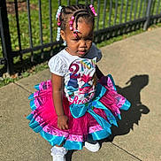 Brooklyn joined the competition — help win amazing prizes! child, toddler, girl, outdoor, sunlight, tutu, braids, beads, trolls, shirt, white_sneakers, sidewalk, shadow, fence, greenery, colorful, fashion, cute, portrait, standing