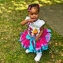 Brooklyn is registered to the contest to win money with this photo: toddler, child, girl, outdoor, grass, tutu_skirt, white_shoes, colorful_clothing, braided_hair, beads, cute, summer, sunlight, nature, portrait, standing, playful, fashion, casual, expression