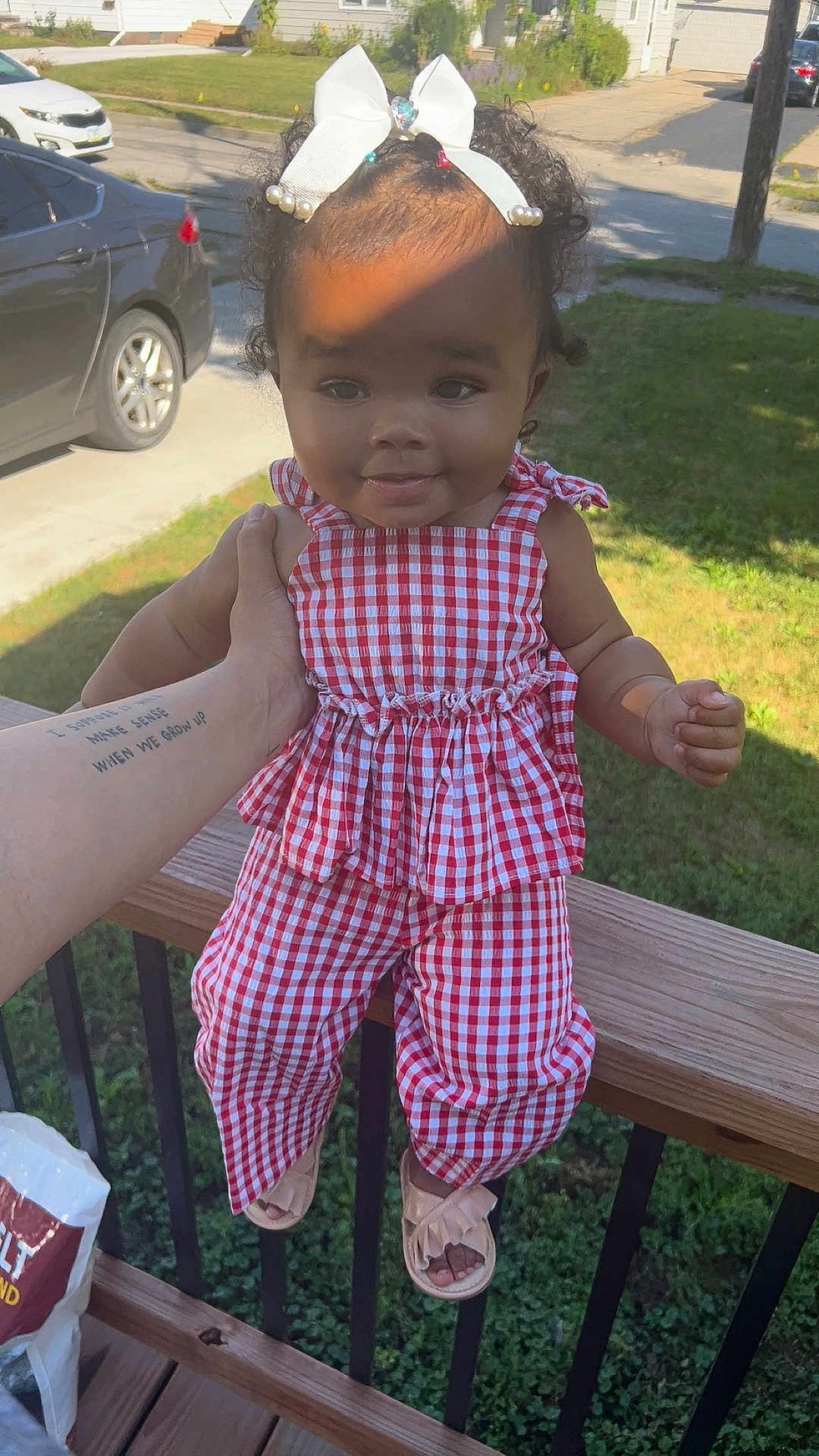 Dezire joined the competition — help win amazing prizes! toddler, child, baby, outdoor, sunlight, curly_hair, white_bow, red_checkered_outfit, sandals, hand_holding, smiling, suburban, street, car, house, grass, wooden_rail, portrait, person, happy