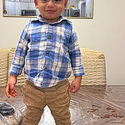 Jason joined the competition — help win amazing prizes! toddler, child, boy, standing, blue_shirt, plaid, khaki_pants, brown_shoes, indoor, table, plastic_cover, mirror, reflection, kitchen, smile, curly_hair, eyes, face, casual_clothing, home