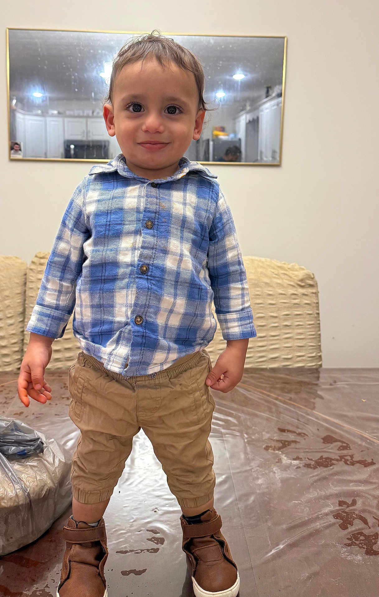Jason joined the competition — help win amazing prizes! toddler, child, boy, standing, blue_shirt, plaid, khaki_pants, brown_shoes, indoor, table, plastic_cover, mirror, reflection, kitchen, smile, curly_hair, eyes, face, casual_clothing, home