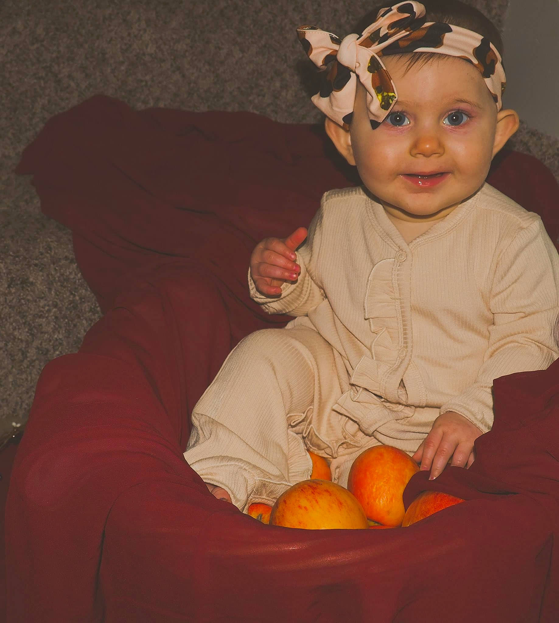 Kimber is registered to the contest to win money with this photo: arm, baby, baby_toddler_clothing, clementine, dress, eye, face, fruit, hand, happy, headband, headpiece, headwear, human_body, joy, natural_foods, orange, person, sleeve, smile