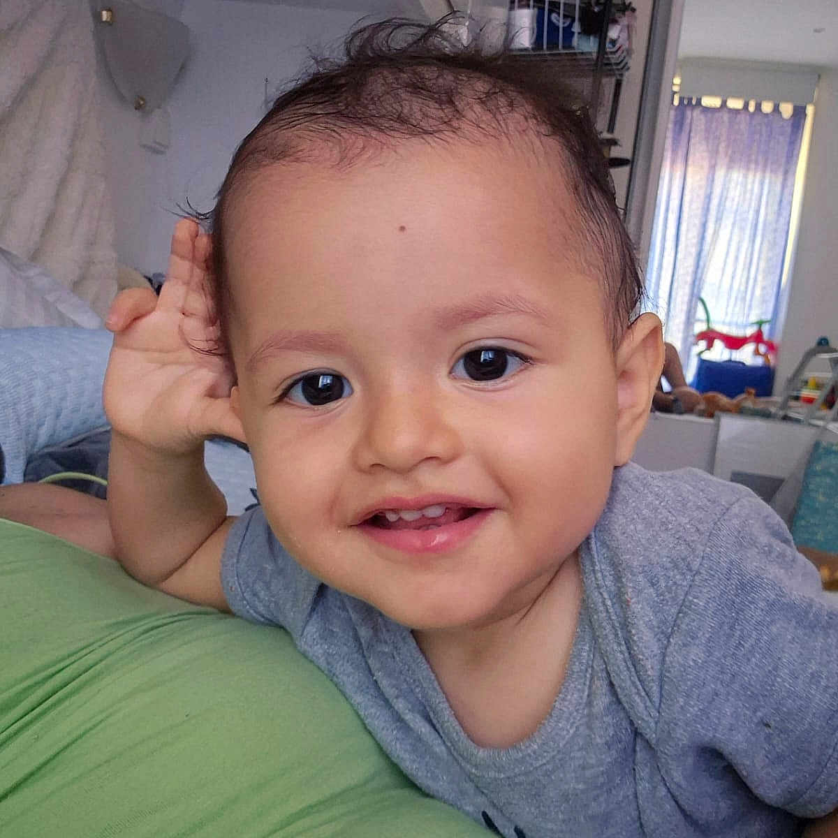 Gabriel a rejoint le concours — aidez-le/la à gagner de superbes lots ! baby, child, curly_hair, curtains, cute, face, furniture, green_surface, grey_shirt, happy, home, indoor, person, playful, portrait, smile, toddler, toys, window, young_child