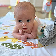 Lottie is registered to the contest to win money with this photo: baby, infant, child, play_mat, toy, indoor, curious, lying_down, arms, head, face, eyes, expression, soft_toy, colorful, blanket, floor, cute, young, portrait