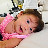 Evelyn joined the competition — help win amazing prizes! baby, child, blue_eyes, smiling, pink_clothing, bed, white_bed, pony_tail, infant, happy, face, cute, indoor, portrait, person, skin, young_child, baby_bottle, soft_light, cozy