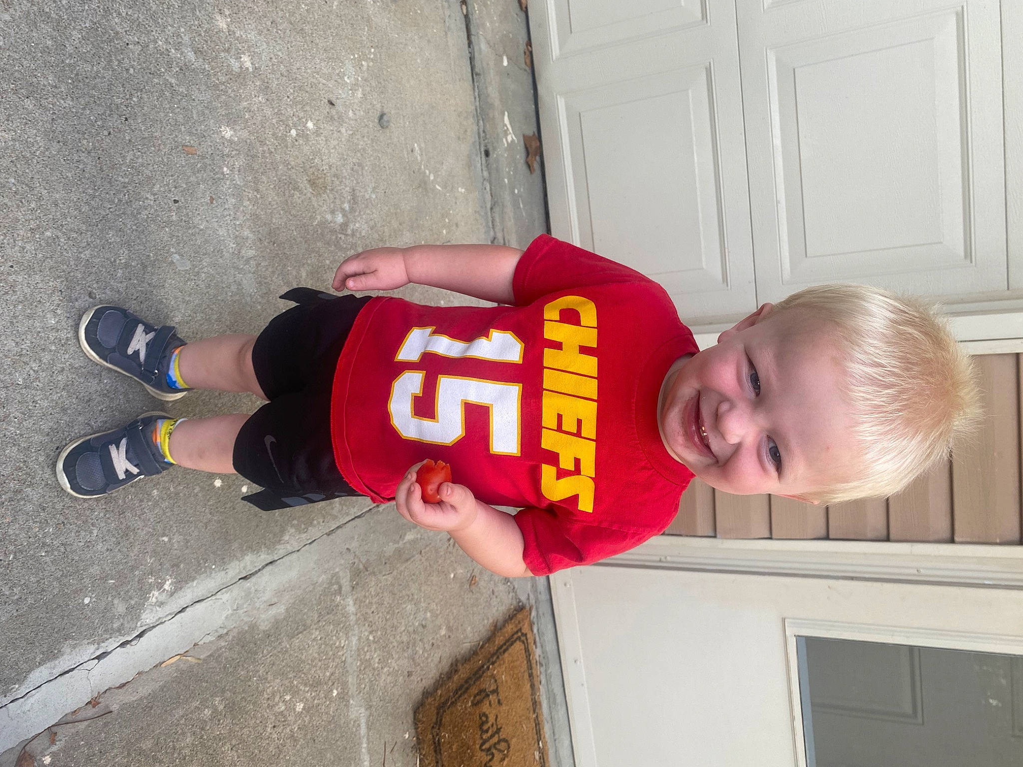 Levi is registered to the contest to win money with this photo: baby_toddler_clothing, carmine, child, fun, glove, hat, human_leg, joy, outdoor_shoe, person, sleeve, smile, sock, sports_uniform, sportswear, t_shirt, toddler, walking_shoe