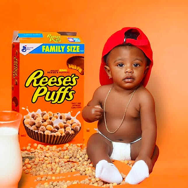 Roman is registered to the contest to win money with this photo: baby, infant, child, sitting, cereal, breakfast, milk, bottle, food, cereal_box, packaging, red_hat, backward_cap, necklace, diaper, socks, orange_background, studio_portrait, advertisement_style, smiling