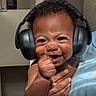 baby, child, infant, smiling, happy, headphones, portrait, close_up, indoor, person, adult, holding, arms, face, eyes, hair, hand, blue_shirt, joyful, photography