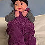Athena is registered to the contest to win money with this photo: adorable, baby, bed, blanket, bow, cheeks, clothing, corduroy, eyes, hands, headband, indoor, infant, overalls, pillow, portrait, purple_overall, sitting, sock, sweater